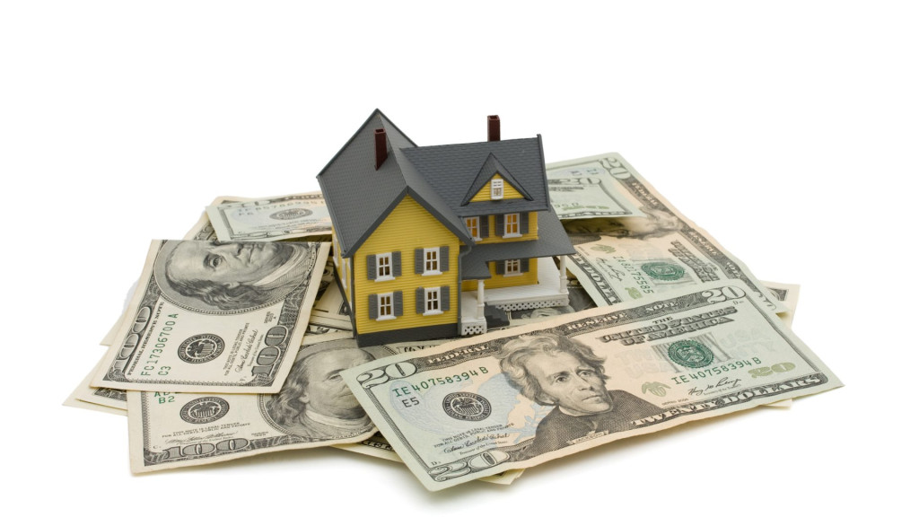 A model of a house with money around it.